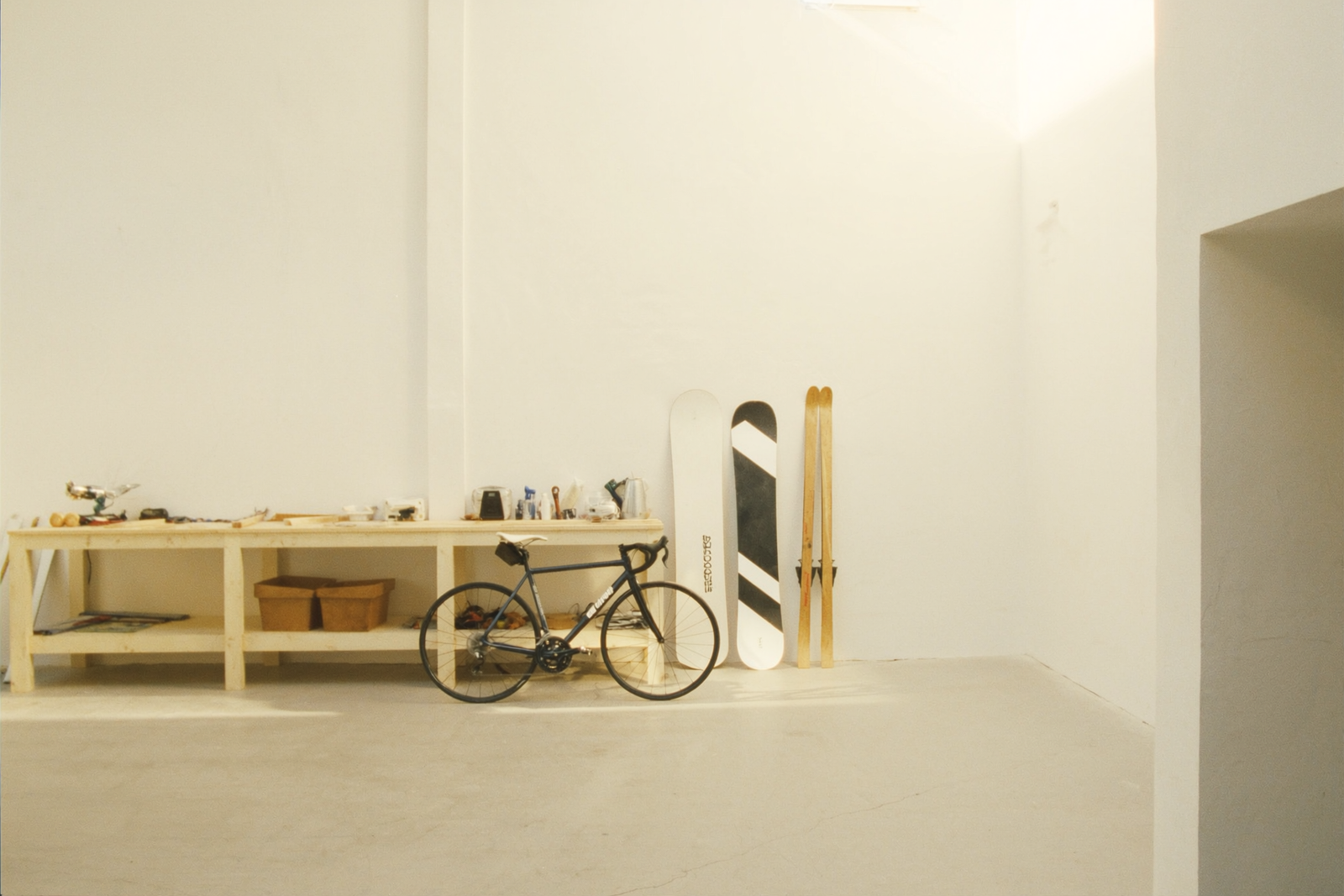 Garage de rider aménagé : vélo de route, snowboard et skis rangés le long d'un établi en bois