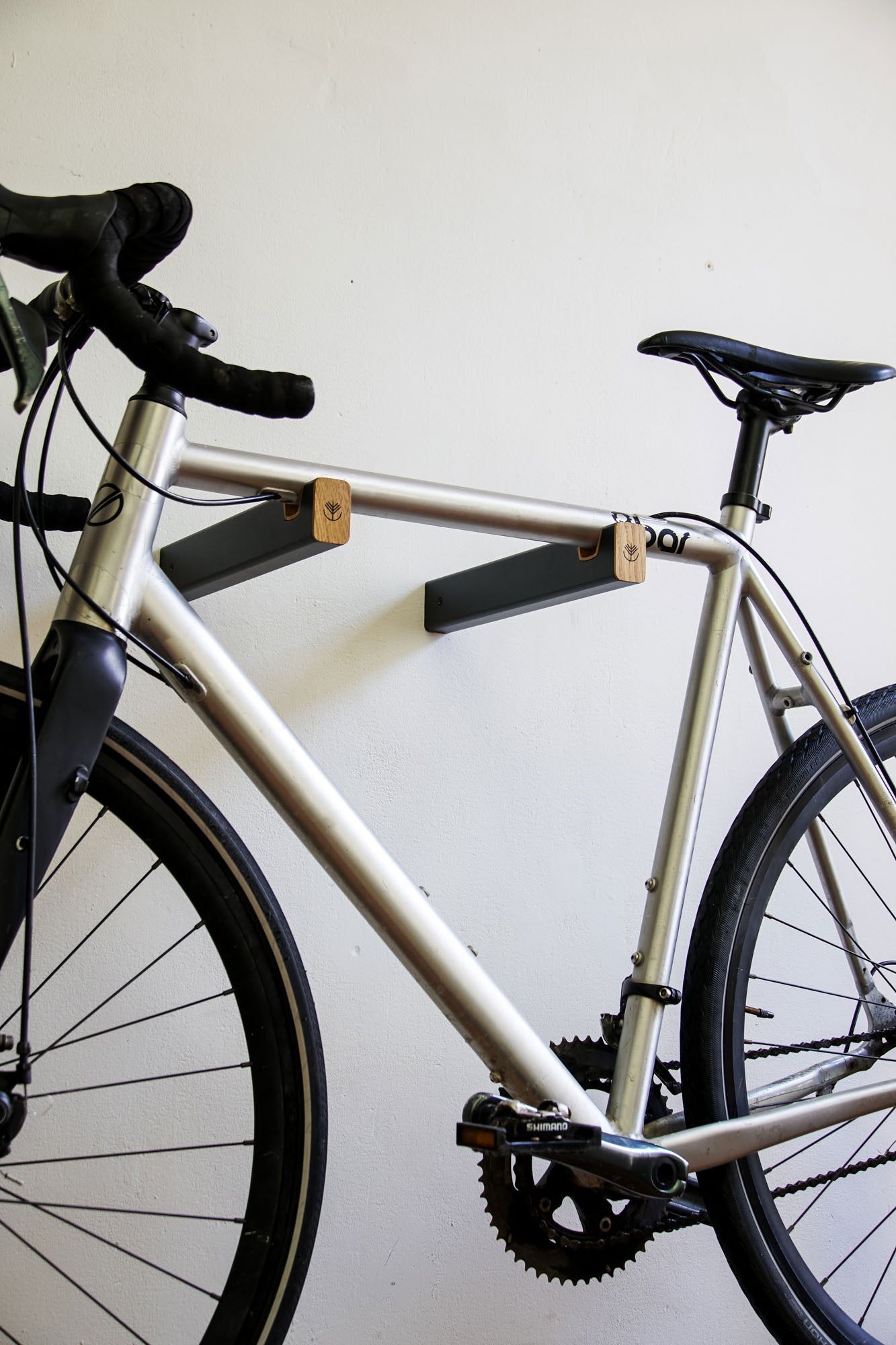 Vélo de route accroché sur un support mural combinant métal et bois de chêne
