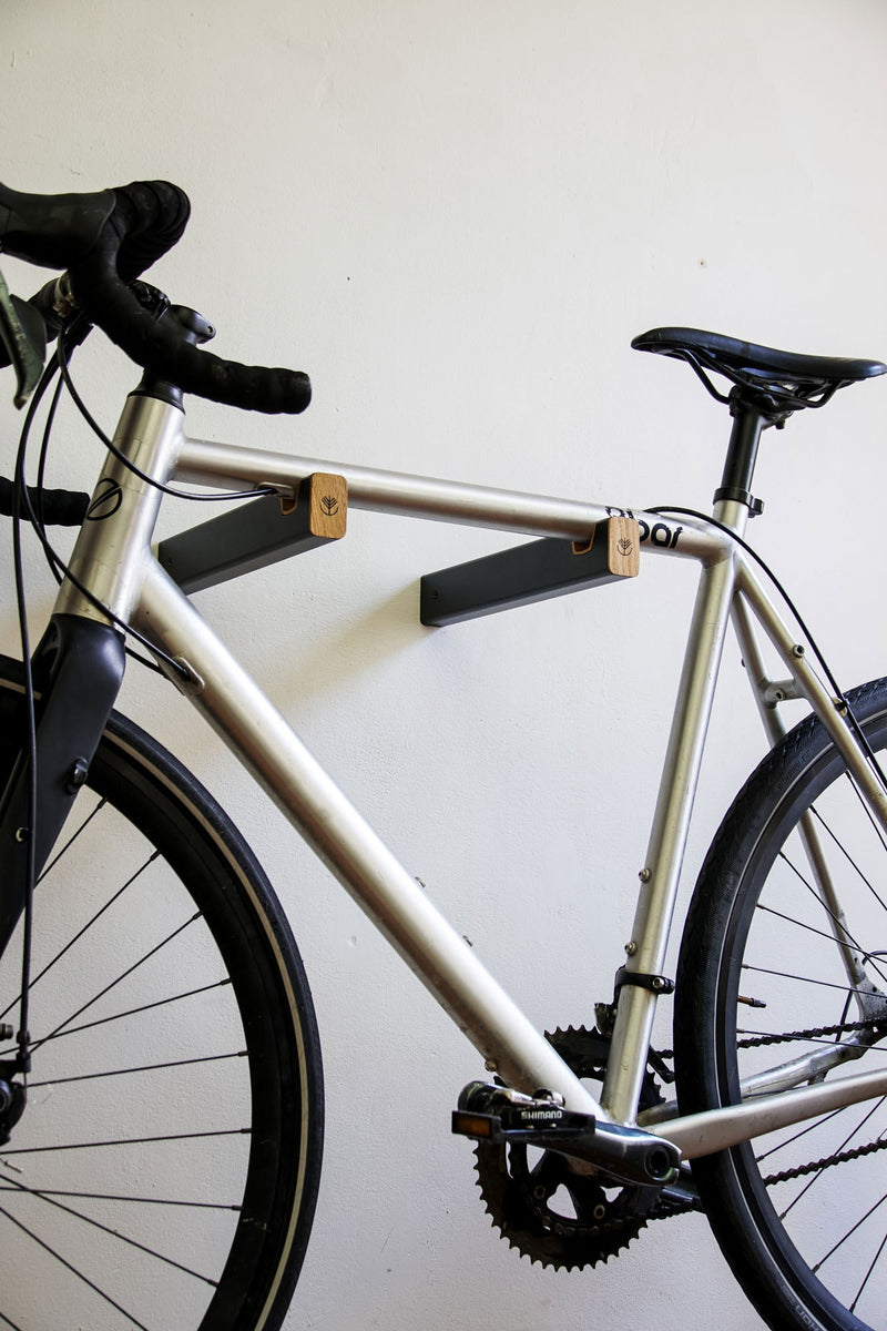 Vélo de route accroché sur un support mural combinant métal et bois de chêne