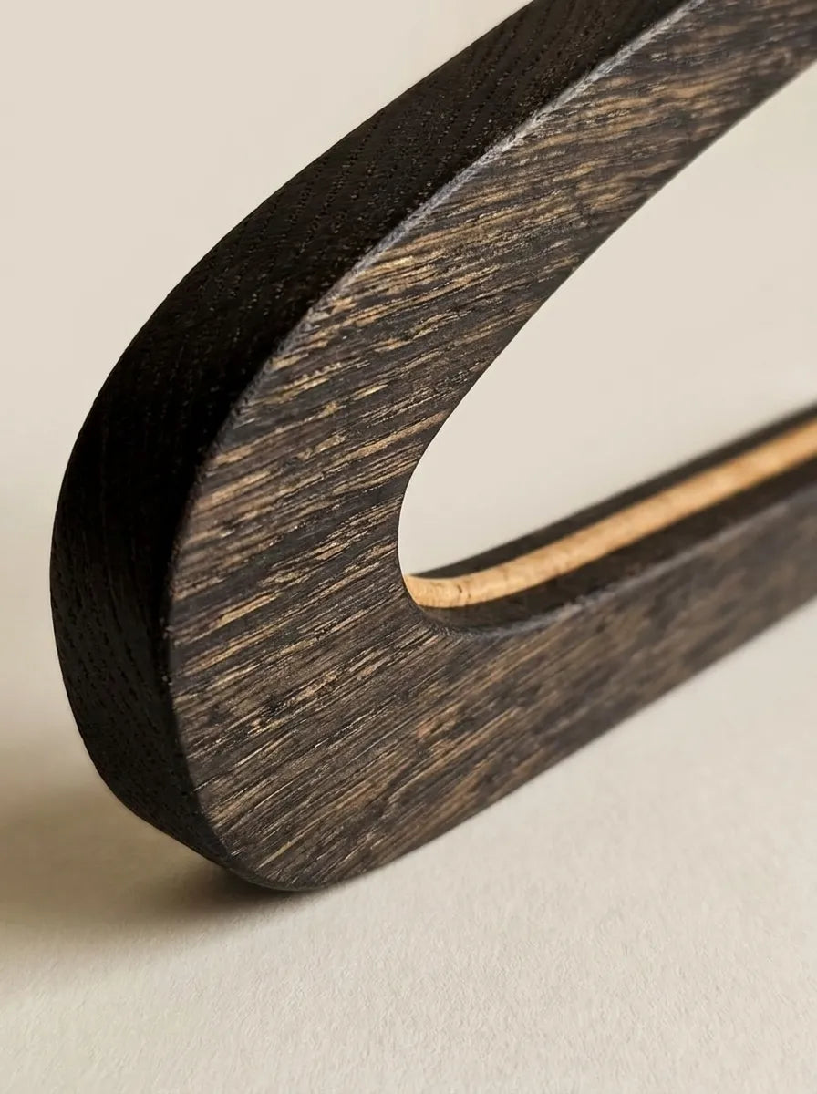 Close-up of black-tinted solid oak showing the wood grain on a surfboard wall rack