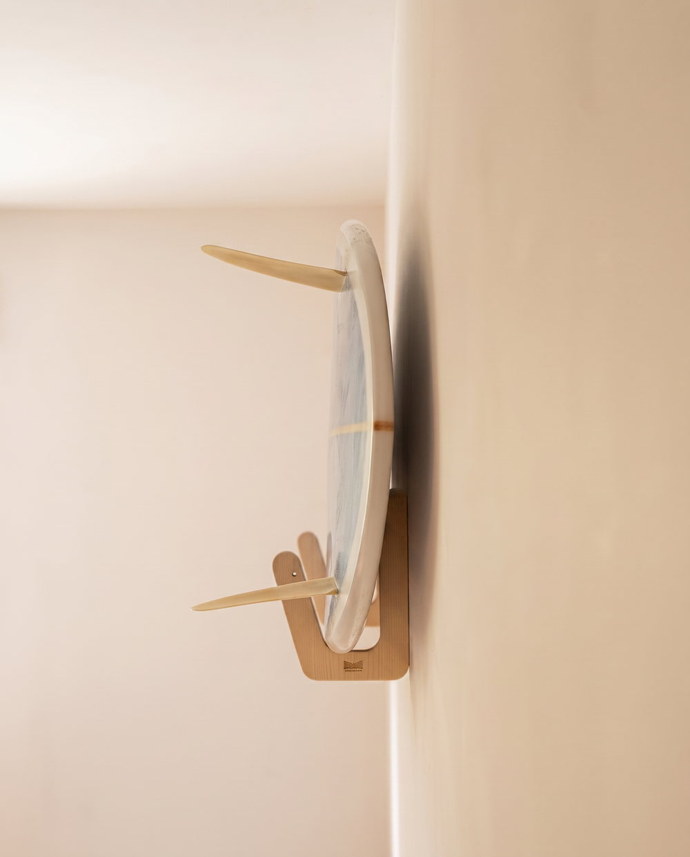 Close-up of the plywood surfboard wall bracket, screw hole and engraved logo