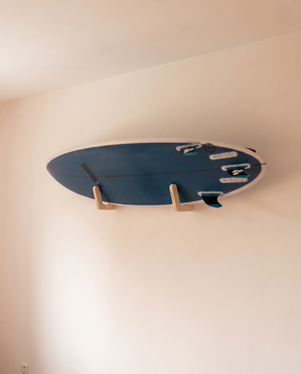 Surfboard leaning forward off the wall, resting on the plywood bracket