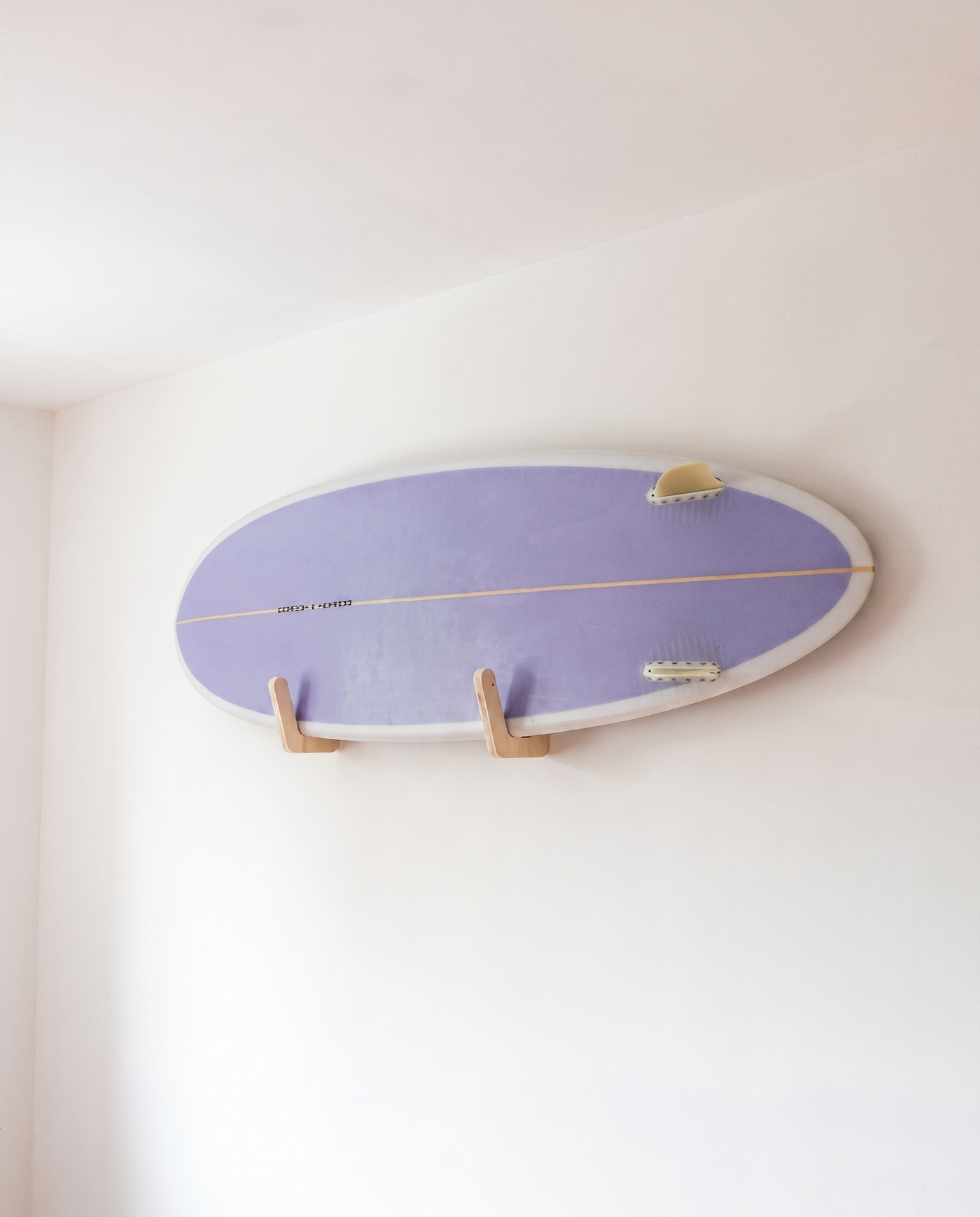 Close-up of a surfboard fin resting in the plywood surfboard wall bracket