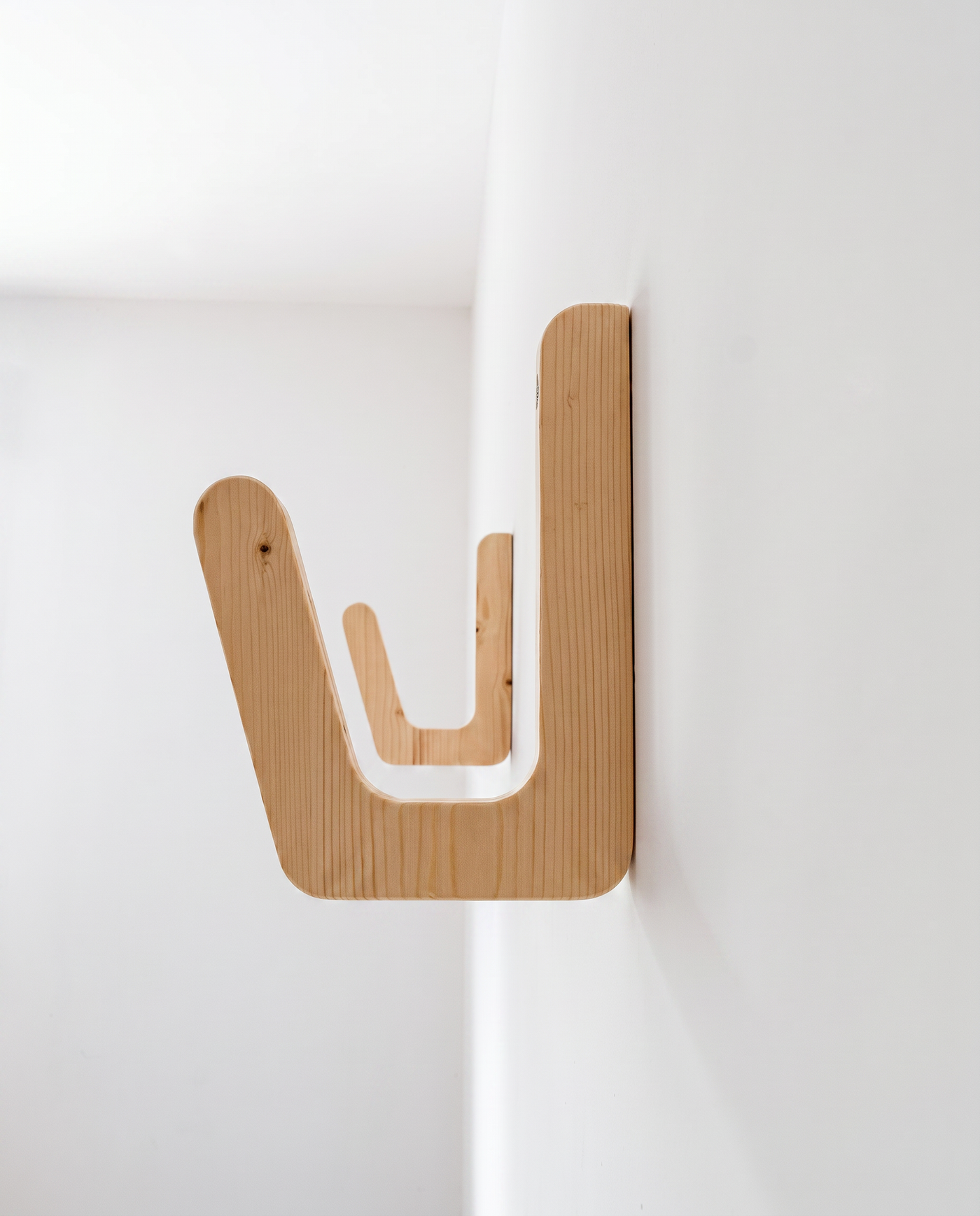 Plywood surfboard wall bracket mounted empty on a white wall