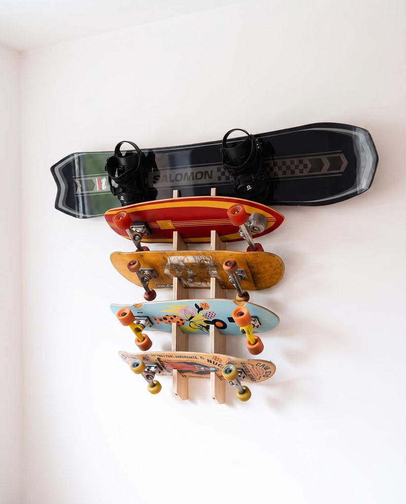 Spruce 3-ply 5-board rack holding a snowboard with bindings and four skateboards on a white wall