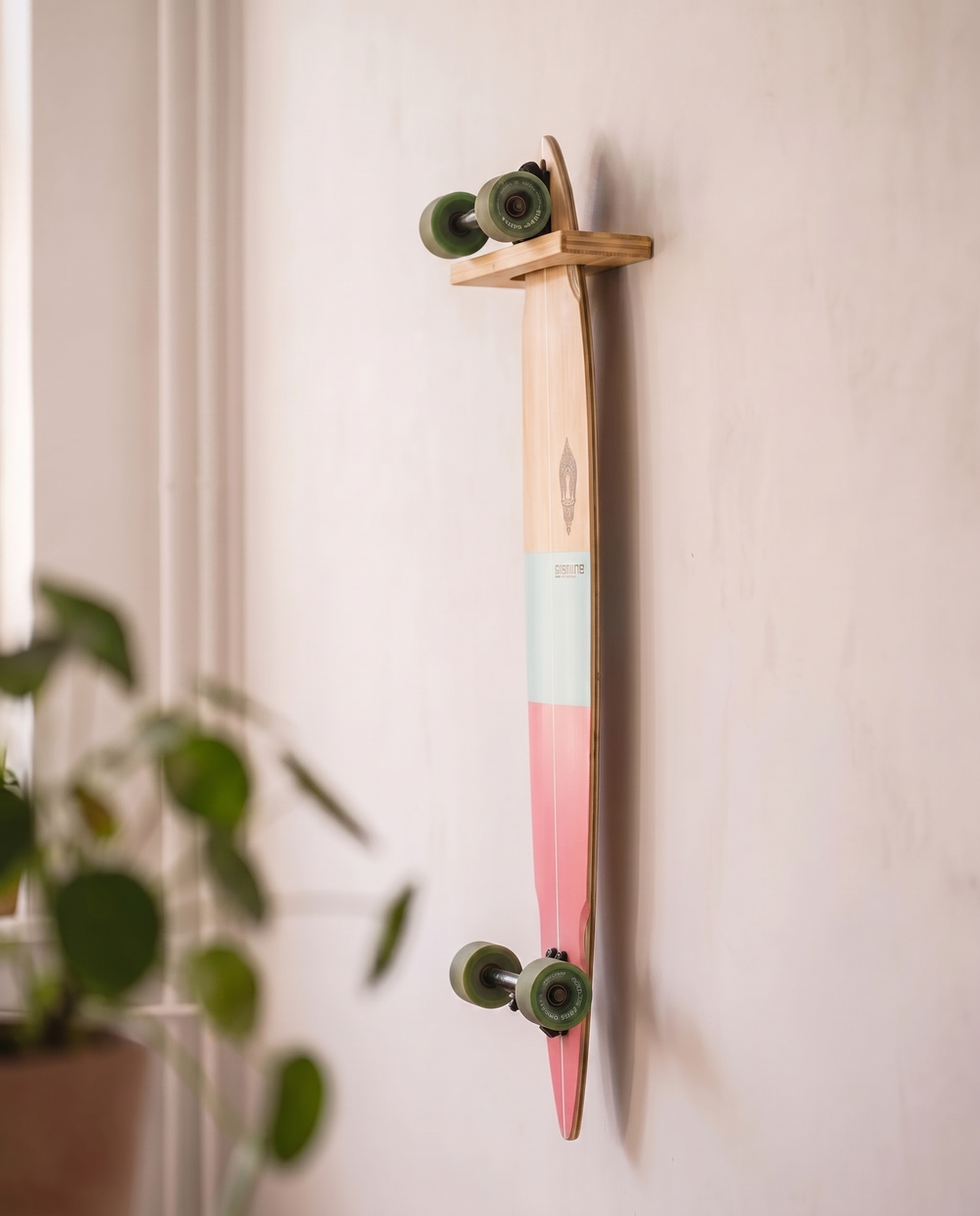 Skateboard hung vertically on a Rack and Ride bamboo wall mount, graphic facing out, off the floor