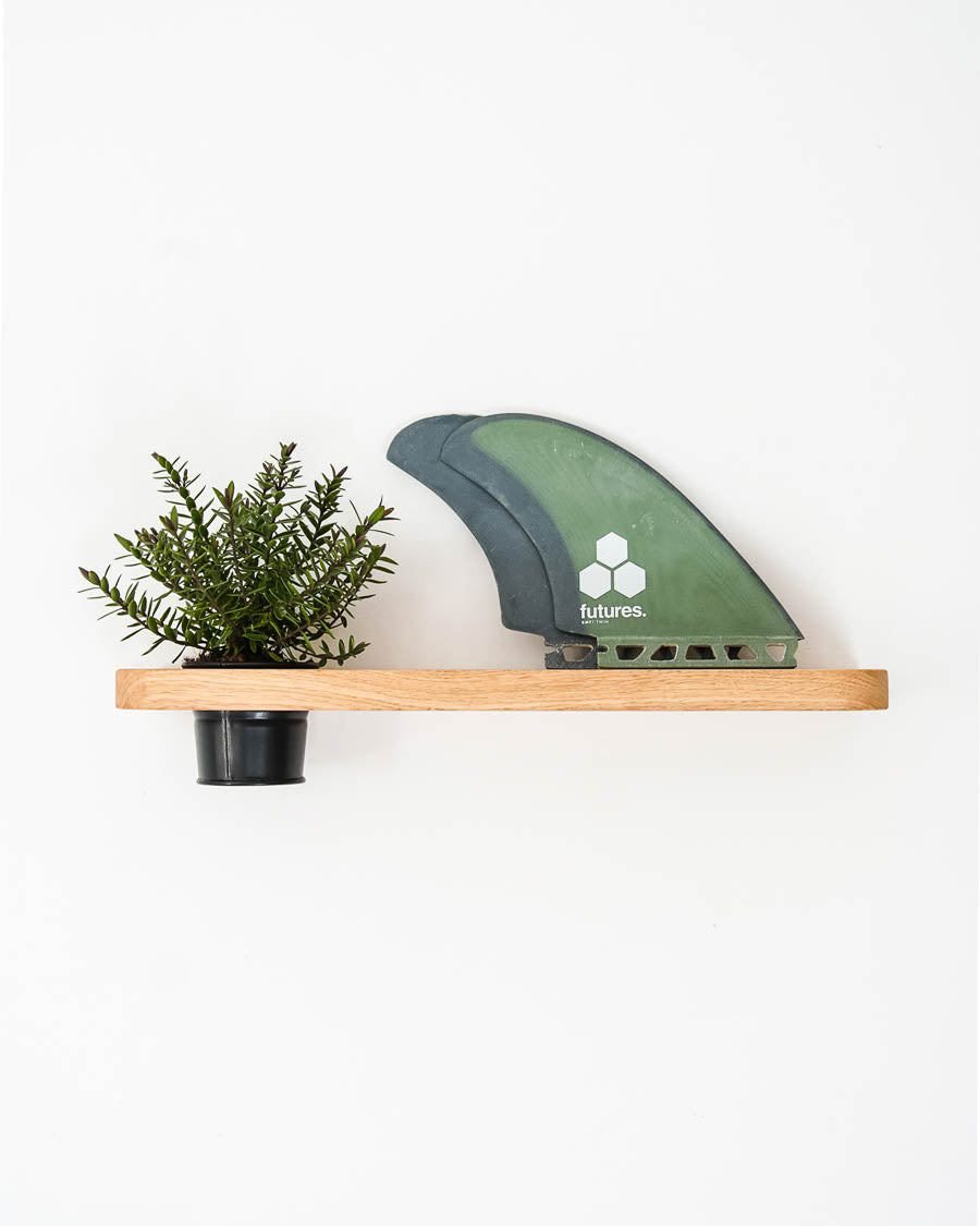 Schwebendes Eichenregal mit einer Pflanze und einer Surfboard-Finne als Wanddeko