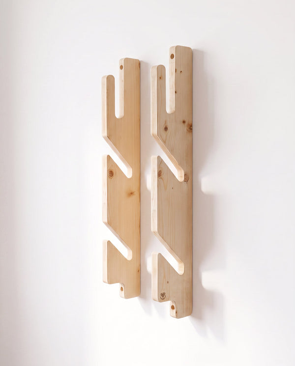 Spruce 3-ply triple boardsport rack mounted empty on a white wall, its two notched rails seen from the front