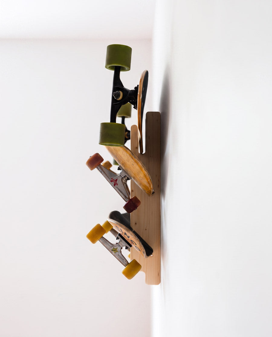 Side view of the loaded spruce 3-ply triple rack, three skateboards held clear of the wall by their decks