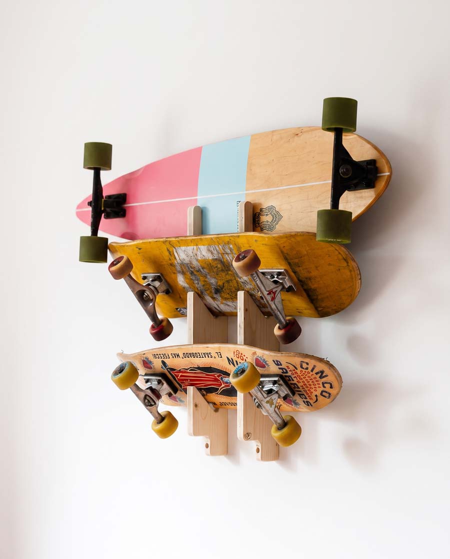 Rack triple en 3 plis épicéa avec un longboard skate, un cruiser et un deck de street, chacun dans son encoche