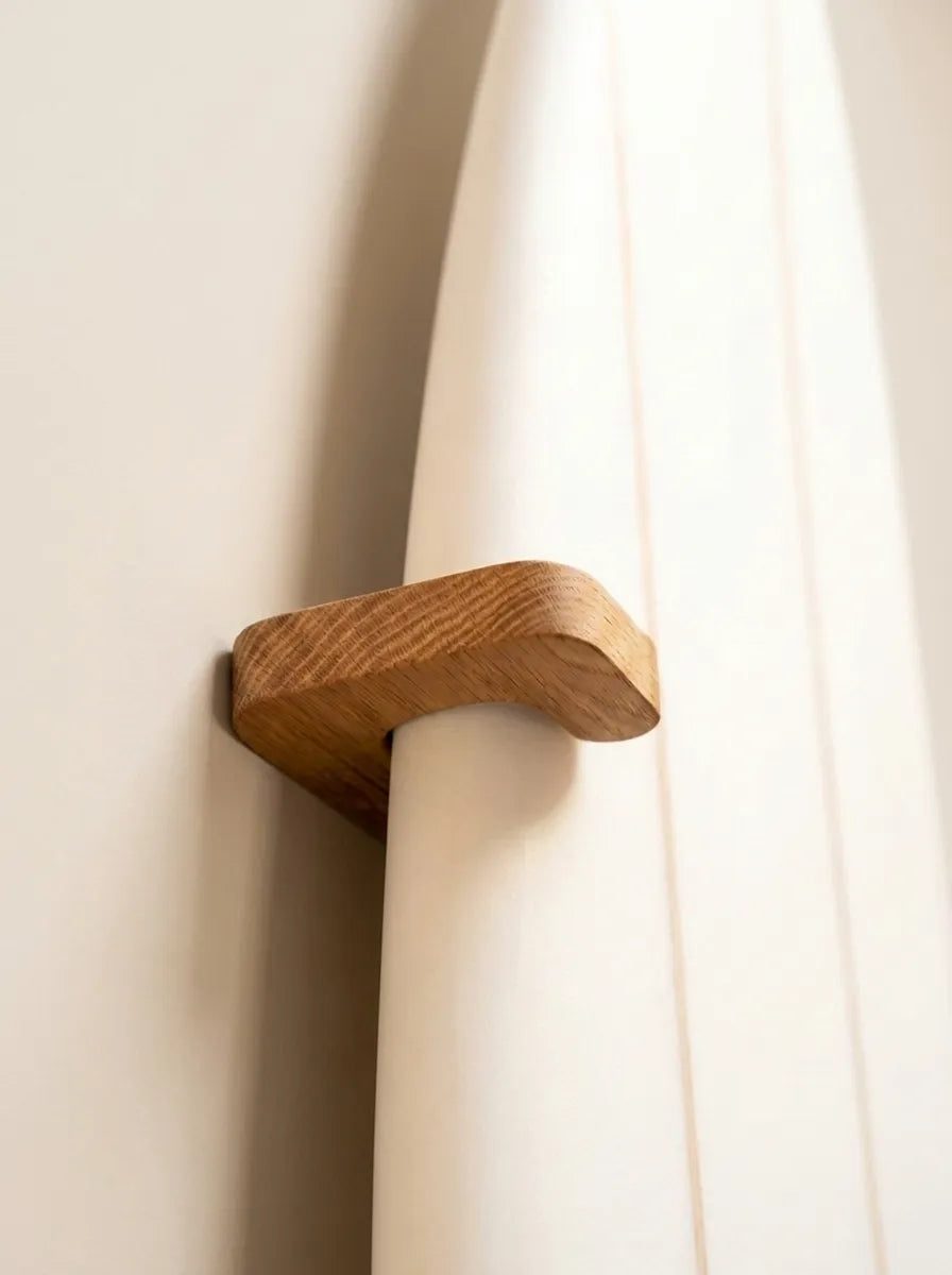 Eichenauflage der Wandhalterung an der Rail eines weißen Surfboards, die das Board flach an die Wand drückt