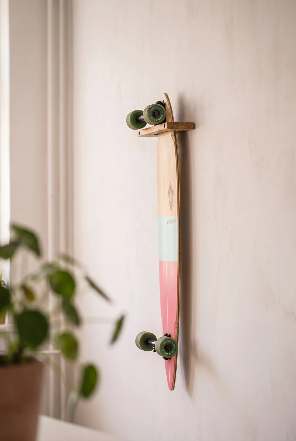 Skate colgado verticalmente en un soporte de pared de roble Rack and Ride, con el gráfico hacia fuera, lejos del suelo